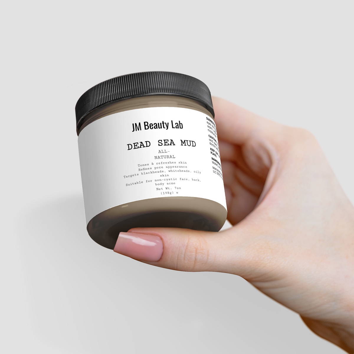 Dead Sea Mud jar held up toward camera, black lid and label facing forward