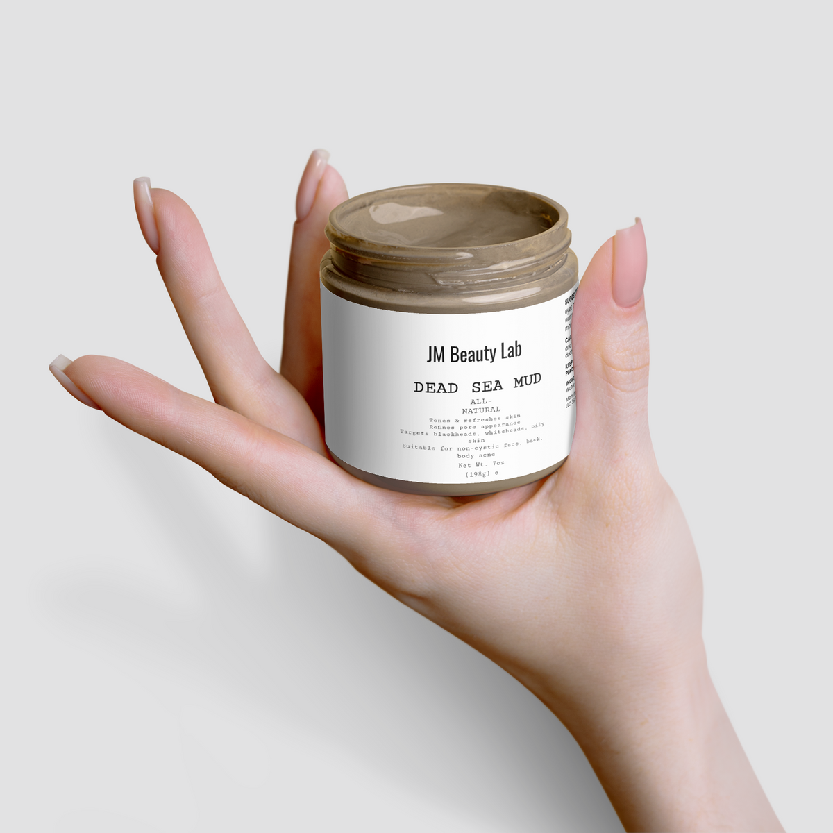 Dead Sea Mud jar with lid open, hands holding the open cosmetic container