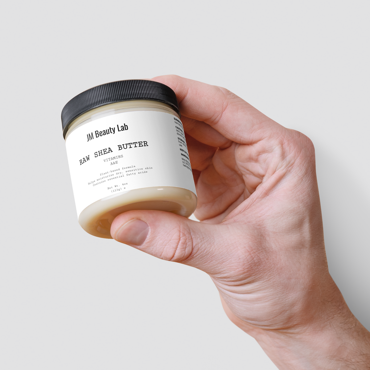 Raw shea butter jar held and tilted, showing jar side and black lid