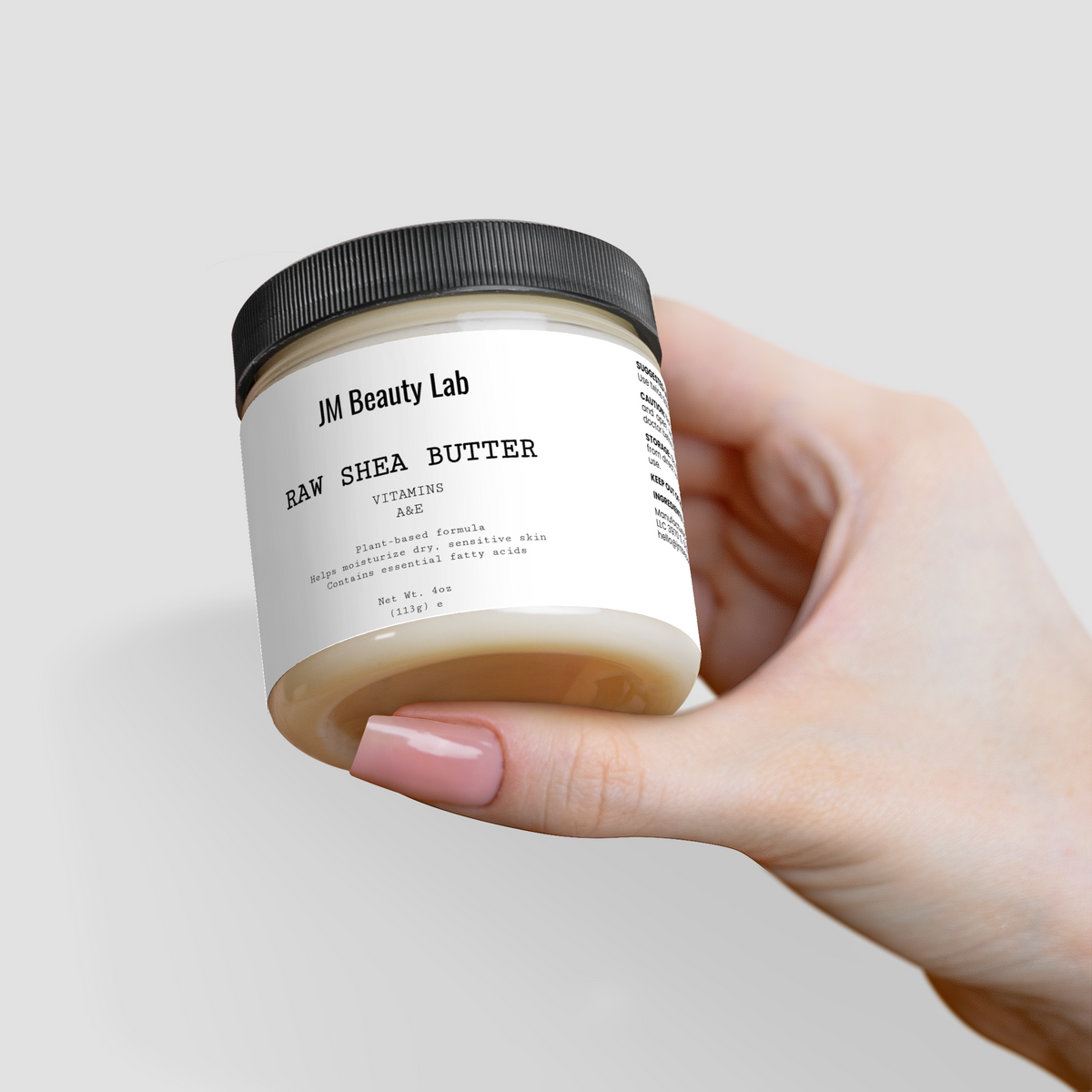 Raw shea butter jar close-up in hand, front label and black lid visible